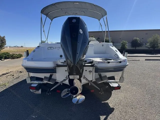 Slide: The Image of 2020 Tahoe 2150 boat with outboard motor and canopy, parked on gravel. - 12