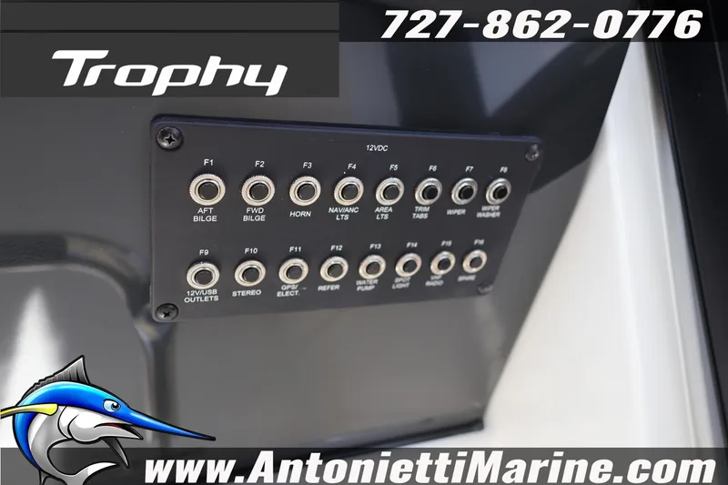 Slide: The Image of Control panel of 2025 Trophy T 25 Pilothouse boat with various switches and website branding. - 18