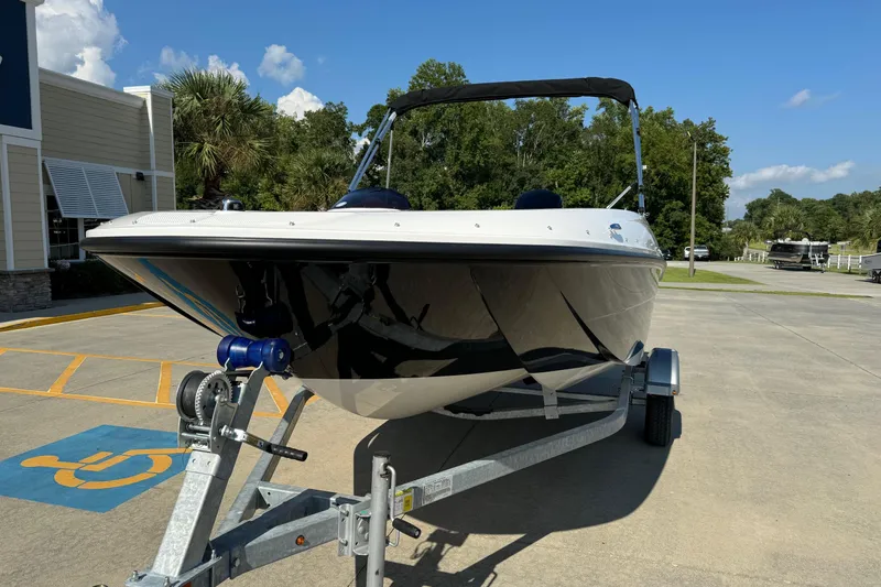 Slide: The Image of 2025 Bayliner Element E16 boat on trailer, parked outdoors under clear blue sky. - 2