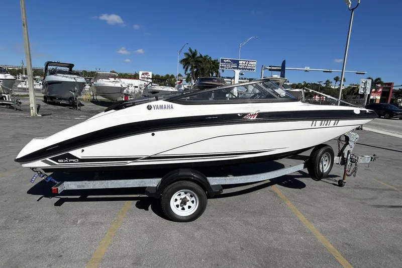 The Image of 2019 Yamaha Boats SX190 on trailer, parked outdoors under clear blue sky. - 1