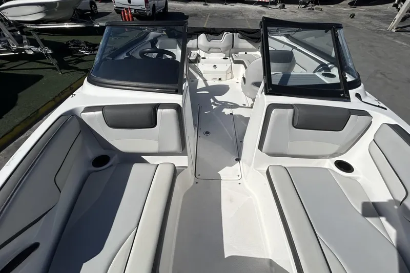 Slide: The Image of 2019 Yamaha Boats SX190 interior with seating and windshield, docked outdoors. - 15