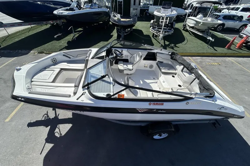 Slide: The Image of 2019 Yamaha Boats SX190, sleek design, spacious interior, parked in a marina setting. - 24