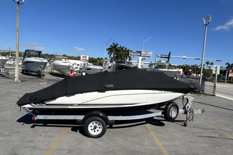 Slide: The Image of 2019 Yamaha Boats SX190 covered on trailer in a boat dealership lot. - 29