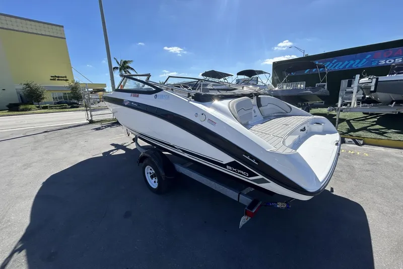 Slide: The Image of 2019 Yamaha Boats SX190 on trailer, parked outdoors under clear blue sky. - 6