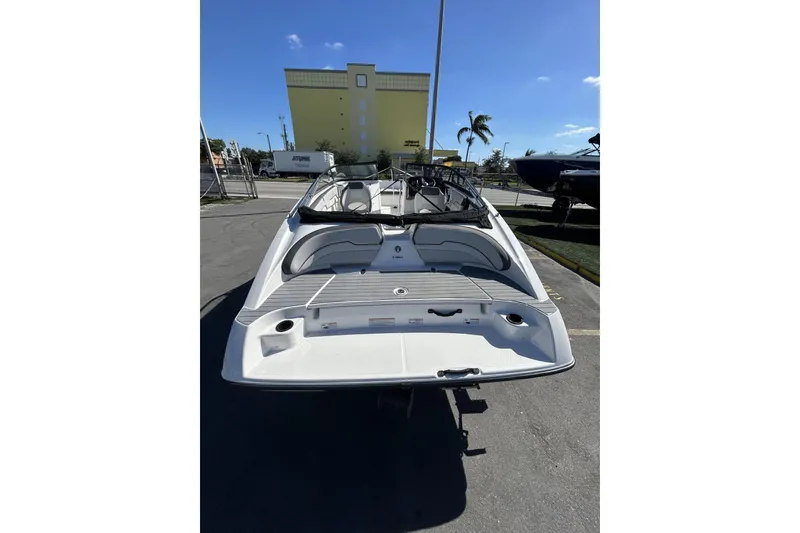 Slide: The Image of 2019 Yamaha Boats SX190, rear view, parked outdoors under clear blue sky. - 7