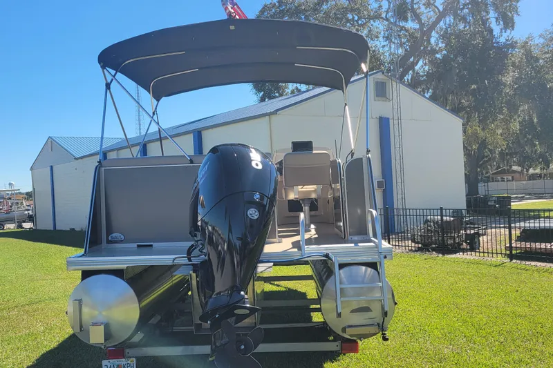 Slide: The Image of 2022 Fiesta 22' Fundeck L Sofa RE Deluxe pontoon boat with outboard motor, parked on grass. - 3