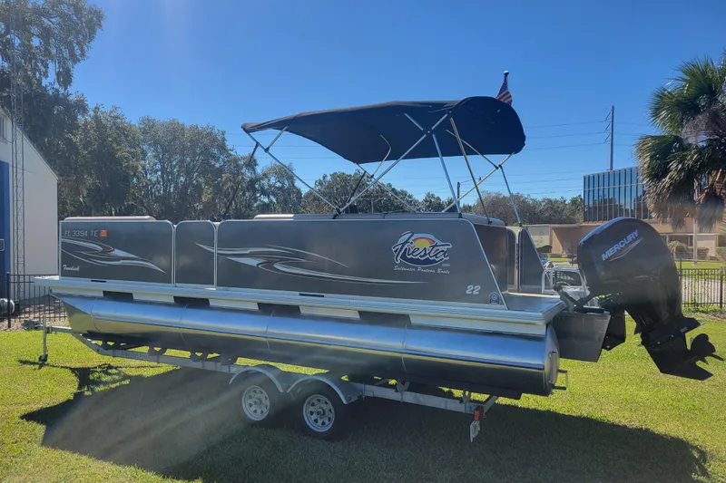 Slide: The Image of 2022 Fiesta 22' Fundeck L Sofa RE Deluxe pontoon boat on trailer, parked on grass. - 4