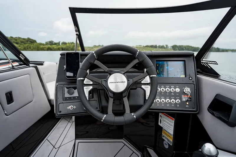 Slide: The Image of Manufacturer Provided Image: 2026 Moomba Mondo boat dashboard with steering wheel and control panel on a lake. - 3