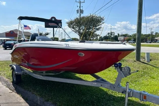 The Image of 2026 Bayliner M17 boat in red on a trailer, parked outdoors. - 1