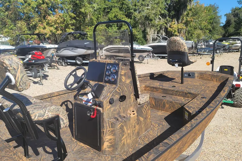 Slide: The Image of 2026 G3 Bay 21 GX Tunnel boat with camo design, parked outdoors among other boats. - 10