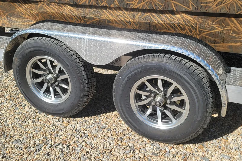 Slide: The Image of Dual wheels on a 2026 G3 Bay 21 GX Tunnel boat trailer, parked on gravel. - 25