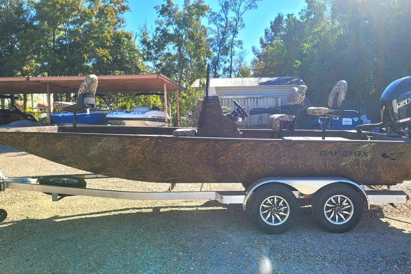 Slide: The Image of 2026 G3 Bay 21 GX Tunnel boat on trailer, camo design, parked outdoors. - 5