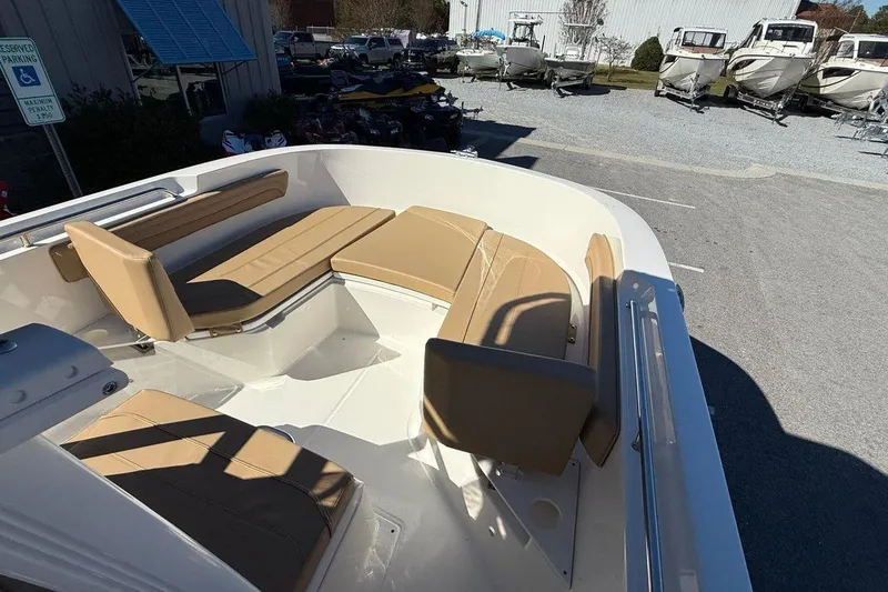 Slide: The Image of 2026 Bayliner Trophy T22CC boat with tan seating, parked outdoors. - 12