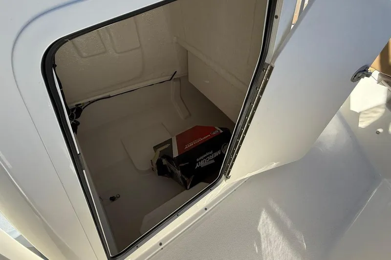 Slide: The Image of 2026 Bayliner Trophy T22CC storage compartment with Mercury box inside. - 13