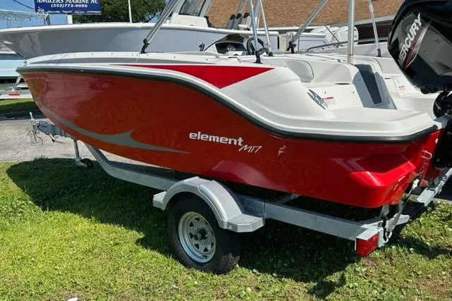 Slide: The Image of 2026 Bayliner M17 boat in red on trailer, parked on grass. - 3
