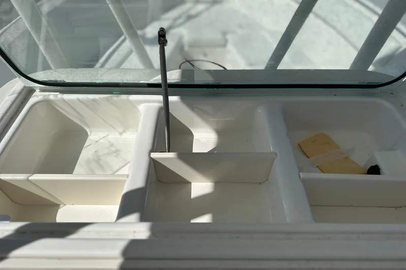 Slide: The Image of 2015 Sailfish 240 CC boat storage compartments with open lid, showcasing interior layout. - 11