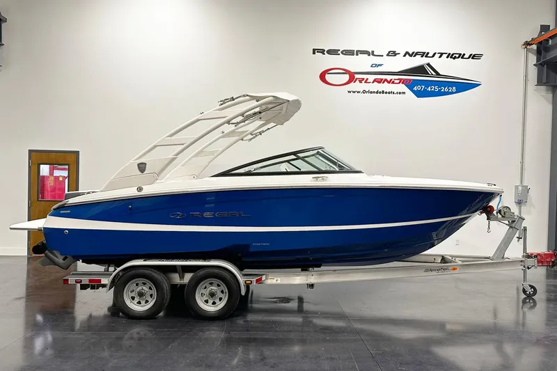 The Image of 2025 Regal LS2 boat in showroom, blue and white design on trailer. - 1