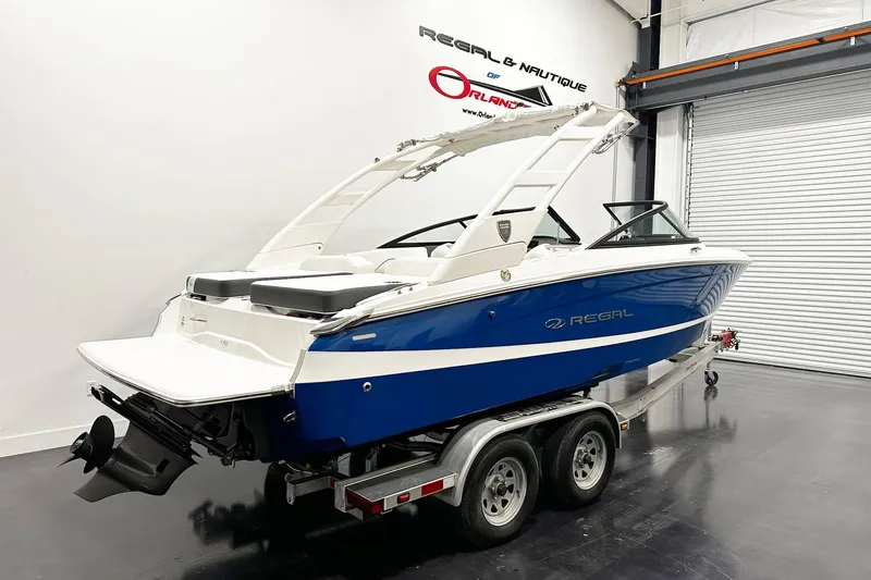 Slide: The Image of 2025 Regal LS2 boat in showroom, blue and white design on trailer. - 3