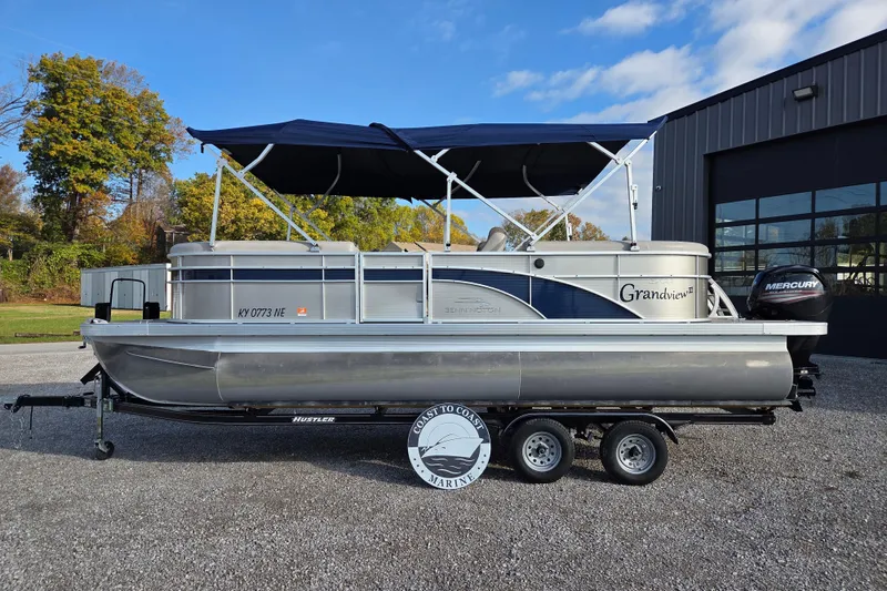 Slide: The Image of 2017 Bennington 22 SSRX pontoon boat with canopy on trailer, parked outdoors. - 2