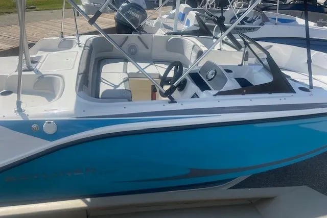 Slide: The Image of 2026 Bayliner M17 boat with blue and white design, docked at a marina. - 2