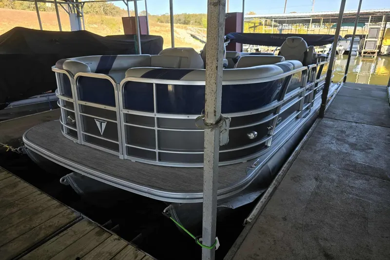 Slide: The Image of 2023 Trifecta 24 RFE pontoon boat docked in a marina. - 2
