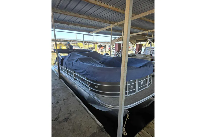 Slide: The Image of 2023 Trifecta 24 RFE pontoon boat covered and docked in a marina. - 3
