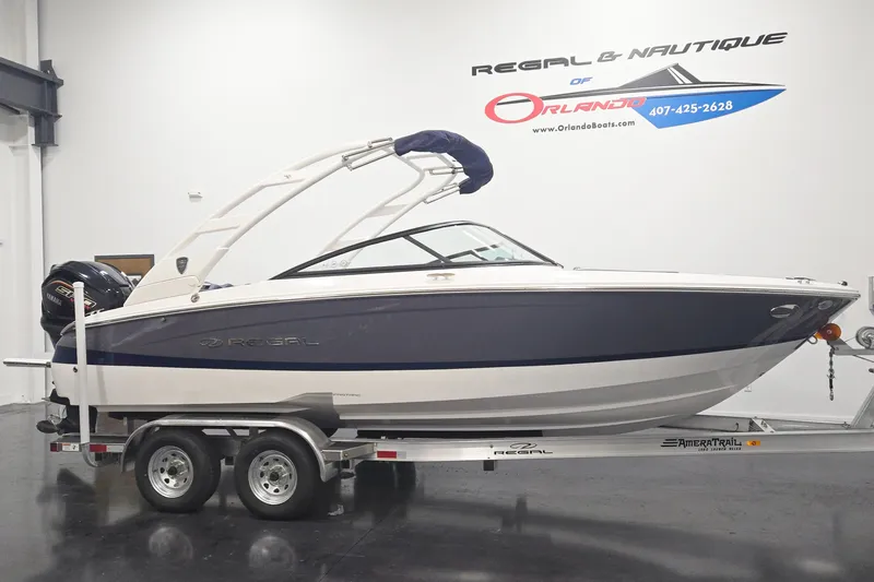 The Image of 2026 Regal LX2 boat on trailer in showroom, featuring sleek design and modern features. - 0
