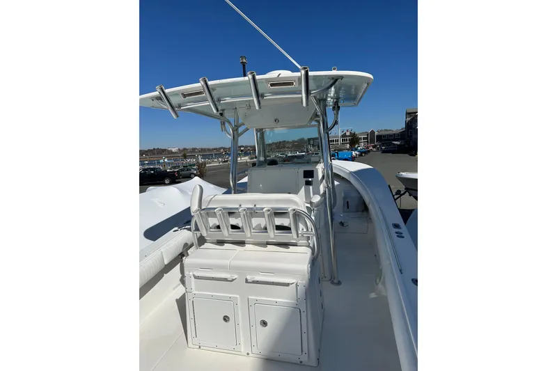 Slide: The Image of 2005 Regulator 32 Forward Seating boat with center console and rod holders, docked under clear sky. - 9