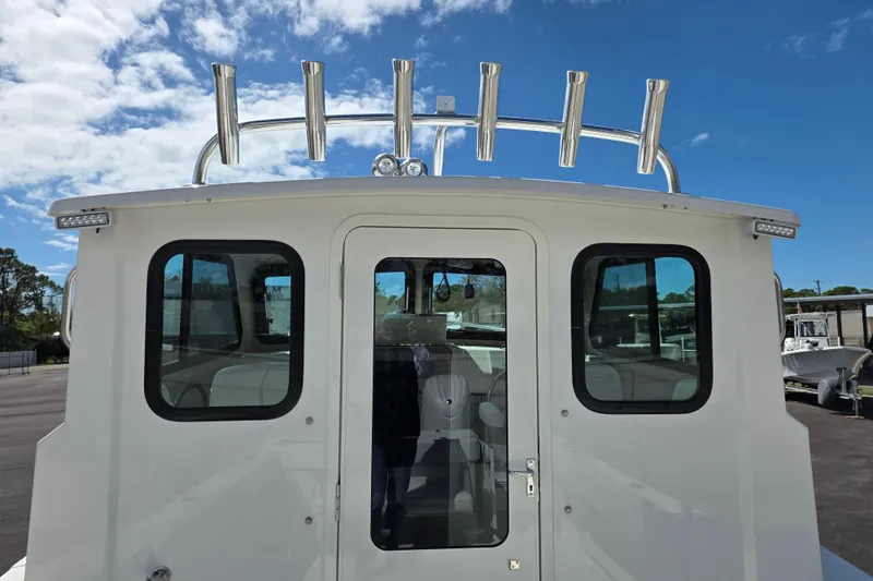 Slide: The Image of 2026 Parker 257 Explorer boat with rod holders, viewed from the rear under a blue sky. - 24