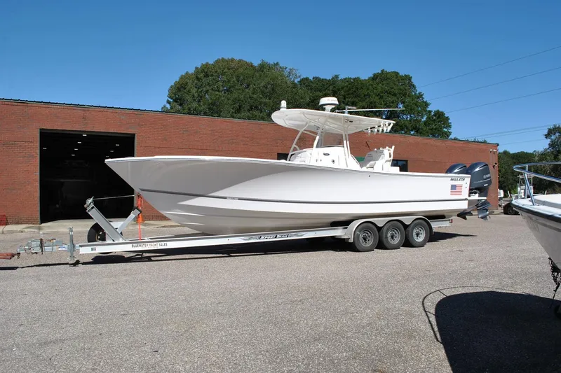 The Image of 2016 Regulator 34 Center Console boat on trailer outside brick building. - 1