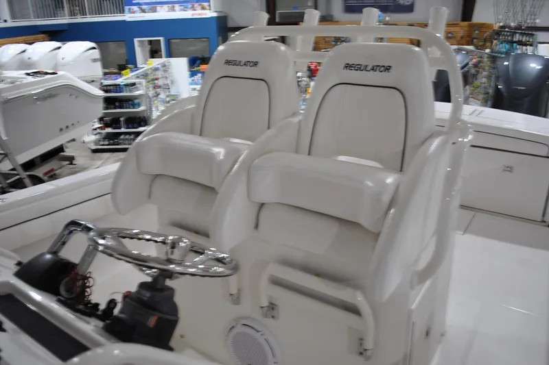 Slide: The Image of 2016 Regulator 34 Center Console boat interior with dual white captain's chairs and steering wheel. - 33
