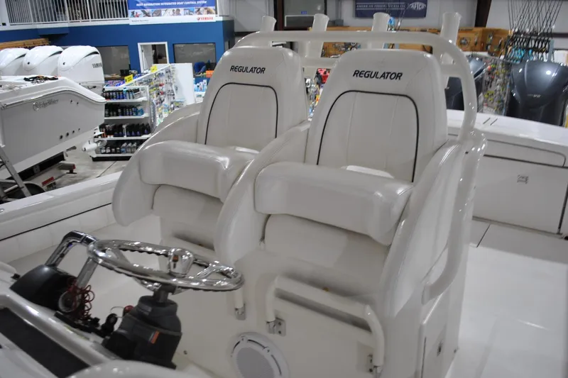 Slide: The Image of 2016 Regulator 34 Center Console boat interior with dual white seats and steering wheel. - 34