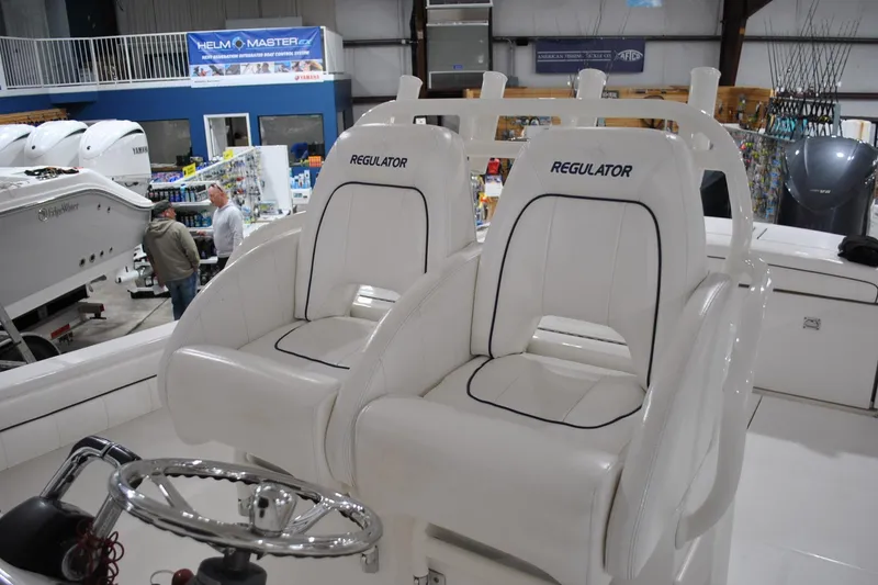 Slide: The Image of 2016 Regulator 34 Center Console boat with white cushioned seats in showroom. - 66