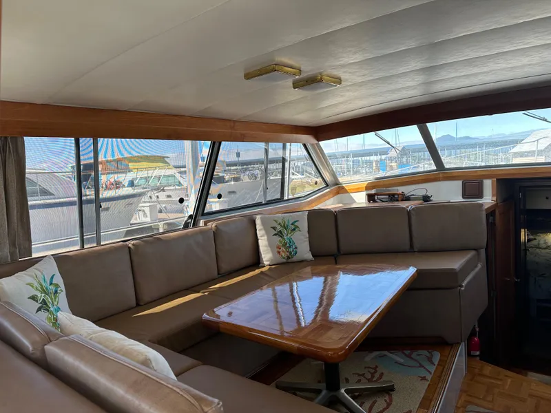 Slide: The Image of 1987 Bayliner 3888 Motoryacht interior with spacious seating and wooden table, dockside view. - 14
