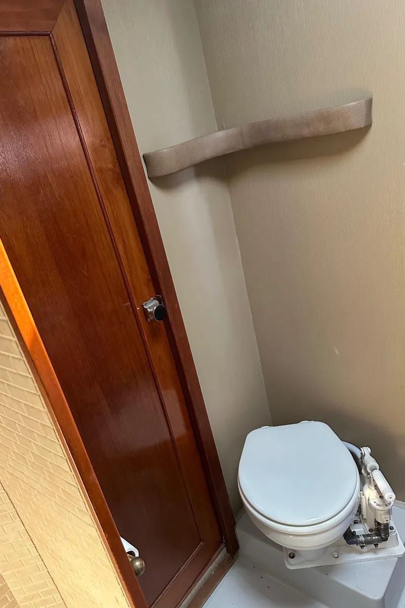 Slide: The Image of 1987 Bayliner 3888 Motoryacht bathroom with wooden door and compact toilet. - 22