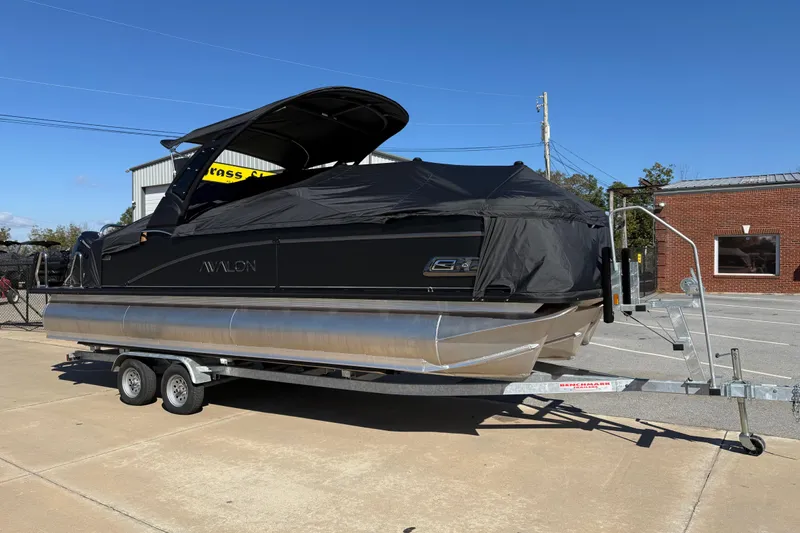 Slide: The Image of 2026 Avalon Catalina Quad Lounger Windshield pontoon boat on trailer, covered, outdoors. - 4