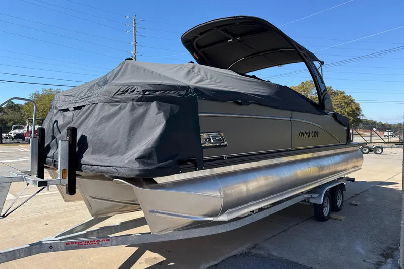 Slide: The Image of 2026 Avalon Catalina Quad Lounger Windshield pontoon boat on trailer, covered and parked outdoors. - 7