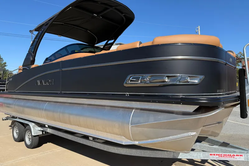 Slide: The Image of 2026 Avalon Catalina Quad Lounger Windshield pontoon boat on trailer, featuring sleek design and tan seating. - 79