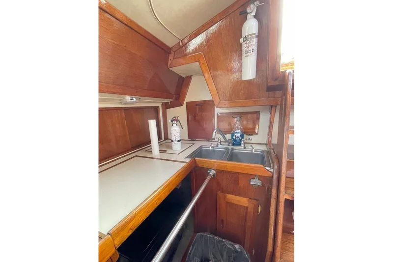 Slide: The Image of 1986 Ericson 381 yacht interior kitchen with wooden cabinetry and dual sink. - 18