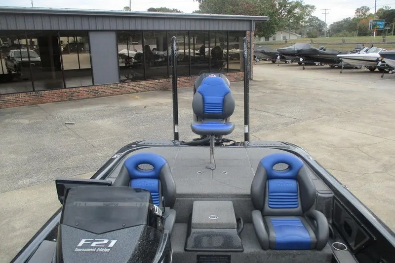 Slide: The Image of 2021 Falcon F21 boat with blue seats, displayed outdoors near a showroom. - 2