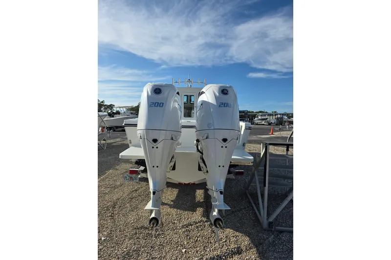 Slide: The Image of 2026 Parker 247 Explorer boat with dual 200 horsepower outboard engines, parked on gravel. - 13