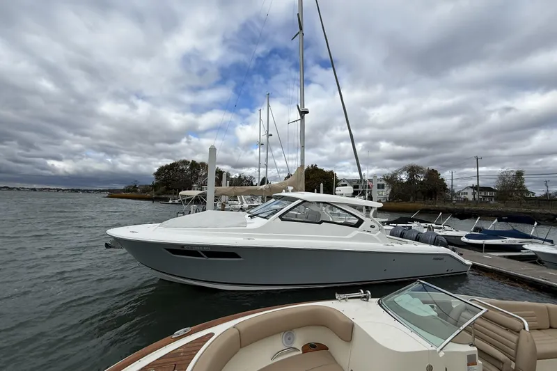 Slide: The Image of 2022 Pursuit DC 365 Dual Console boat docked on a cloudy day. - 1
