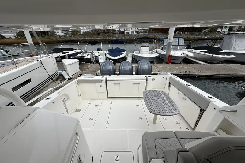 Slide: The Image of 2022 Pursuit DC 365 Dual Console boat docked, featuring spacious deck and seating area. - 20
