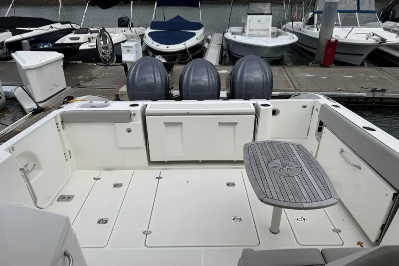 Slide: The Image of 2022 Pursuit DC 365 Dual Console boat interior with seating and table at marina. - 21