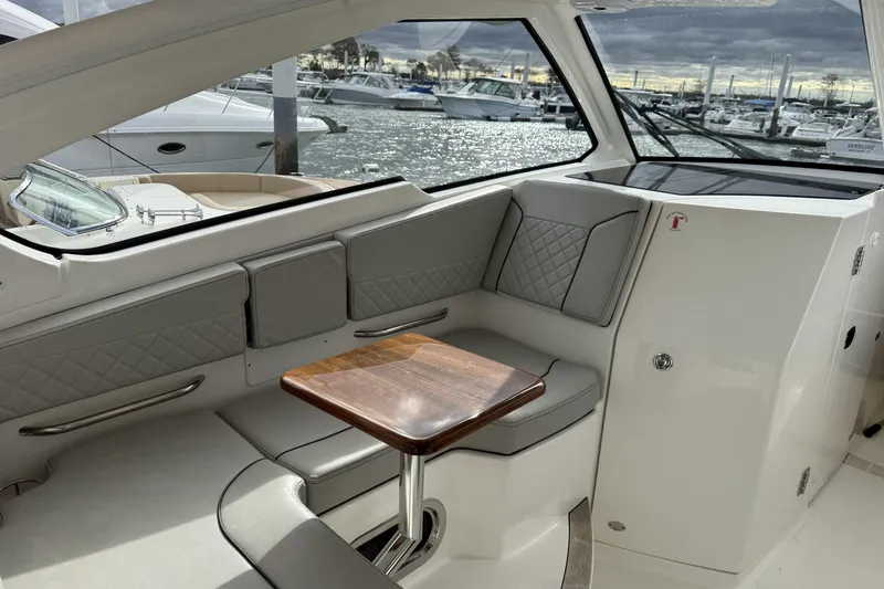 Slide: The Image of 2022 Pursuit DC 365 Dual Console interior with elegant seating and wooden table, docked at marina. - 26