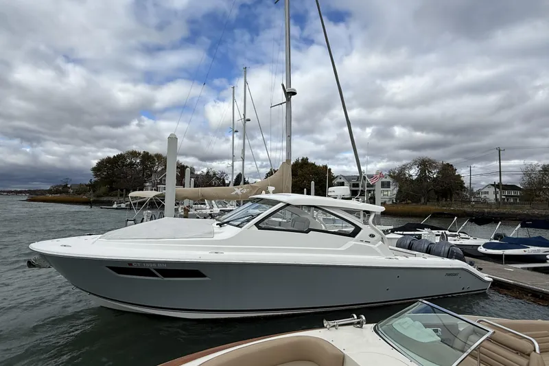 Slide: The Image of 2022 Pursuit DC 365 Dual Console boat docked at marina under cloudy sky. - 3