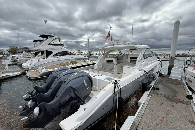 Slide: The Image of 2022 Pursuit DC 365 Dual Console boat docked with Yamaha engines, under cloudy skies. - 7