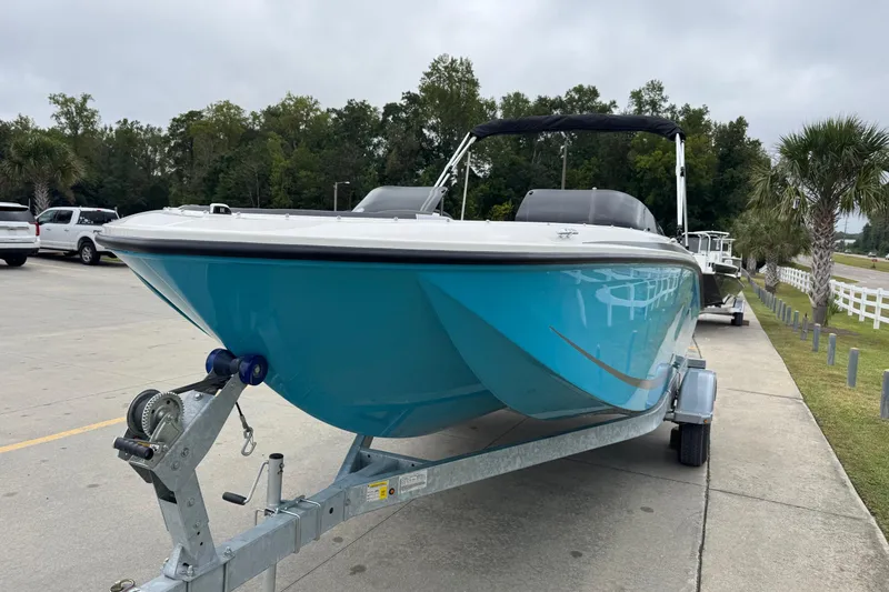 Slide: The Image of 2026 Bayliner M19 boat on trailer, parked outdoors with trees in background. - 2