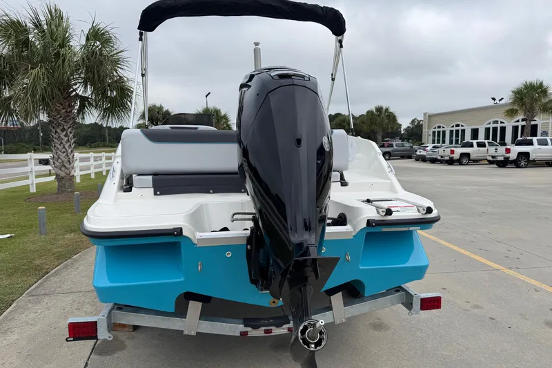 Slide: The Image of 2026 Bayliner M19 boat with outboard motor on trailer, parked near palm trees. - 4