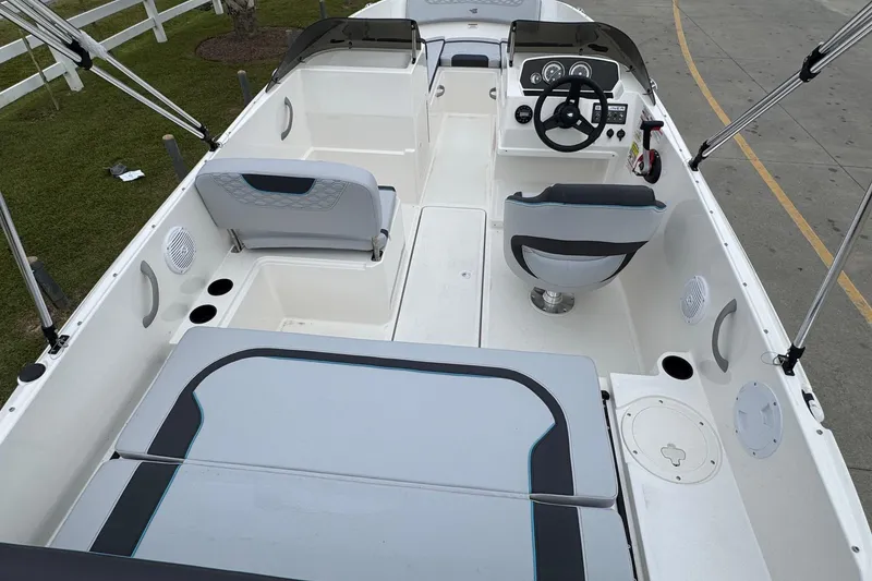 Slide: The Image of 2026 Bayliner M19 boat interior with seating and steering wheel, docked on pavement. - 8